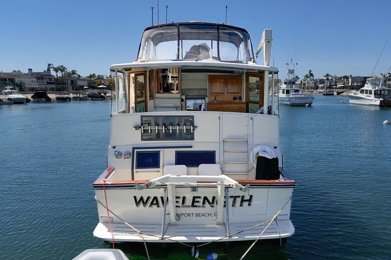 Slide: The Image of 1989 Californian 48 Cockpit Motor Yacht docked in a serene marina setting. - 12