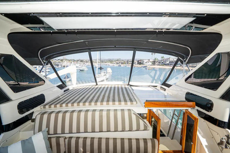 Slide: The Image of Interior view of 1989 Californian 48 Cockpit Motor Yacht with striped seating and marina backdrop. - 29