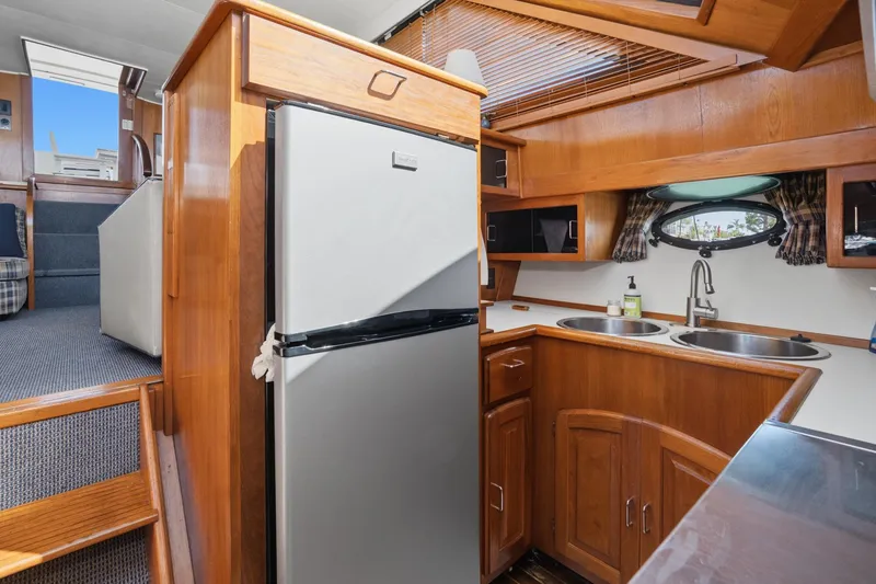Slide: The Image of 1989 Californian 48 Cockpit Motor Yacht interior with wooden cabinetry and modern kitchen amenities. - 40