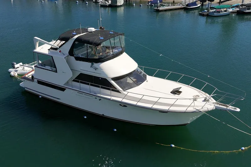 Slide: The Image of 1989 Californian 48 Cockpit Motor Yacht docked in a serene marina setting. - 5