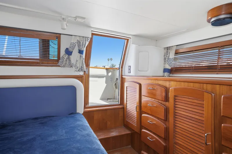 Slide: The Image of Interior of 1989 Californian 48 Cockpit Motor Yacht with wooden cabinetry and blue bedding. - 58