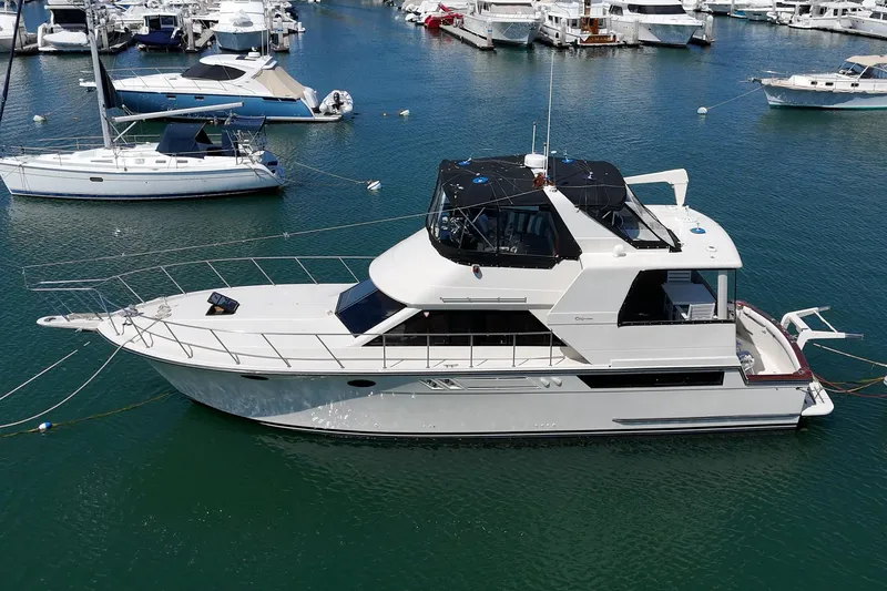 Slide: The Image of 1989 Californian 48 Cockpit Motor Yacht docked in a marina, surrounded by other boats. - 8