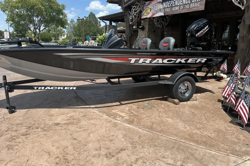 The Image of 2026 Tracker Pro Team 175 Crappie Edition boat displayed outdoors with American flags. - 0