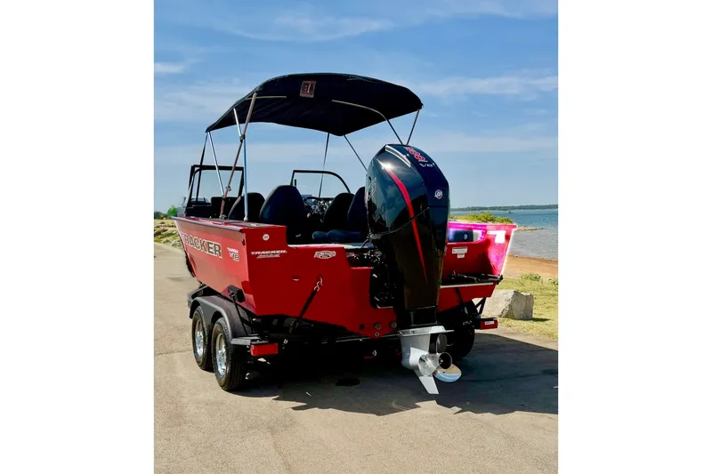 Slide: The Image of Red 2026 Tracker Targa V-18 Combo boat with outboard motor, parked near a lake. - 17