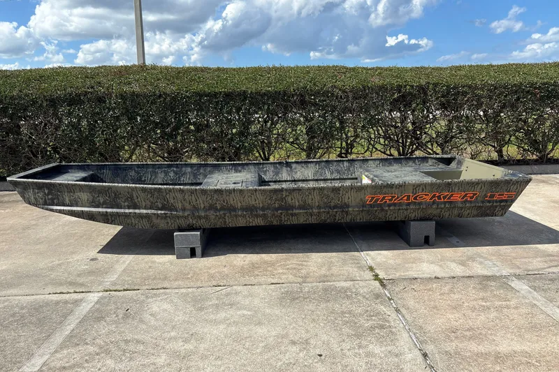 The Image of 2026 Tracker Grizzly 15 Jon boat on concrete blocks, outdoors under a cloudy sky. - 0
