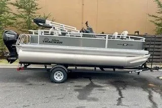 The Image of 2026 Sun Tracker Bass Buggy 18 DLX pontoon boat on trailer, parked outdoors. - 0