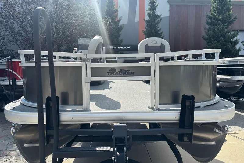 Slide: The Image of 2026 Sun Tracker Bass Buggy 18 DLX pontoon boat, rear view, parked outdoors. - 37
