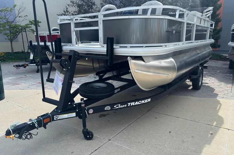 Slide: The Image of 2026 Sun Tracker Bass Buggy 18 DLX pontoon boat on trailer, parked outdoors. - 34