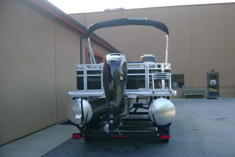 Slide: The Image of 2026 Sun Tracker Fishin' Barge 20 DLX pontoon boat, rear view, parked outdoors. - 4