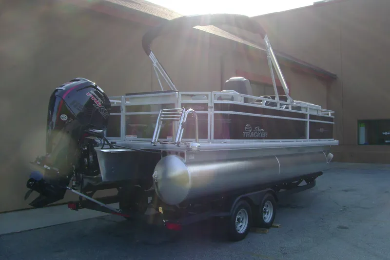 Slide: The Image of 2026 Sun Tracker Fishin' Barge 20 DLX pontoon boat with outboard motor on trailer. - 2
