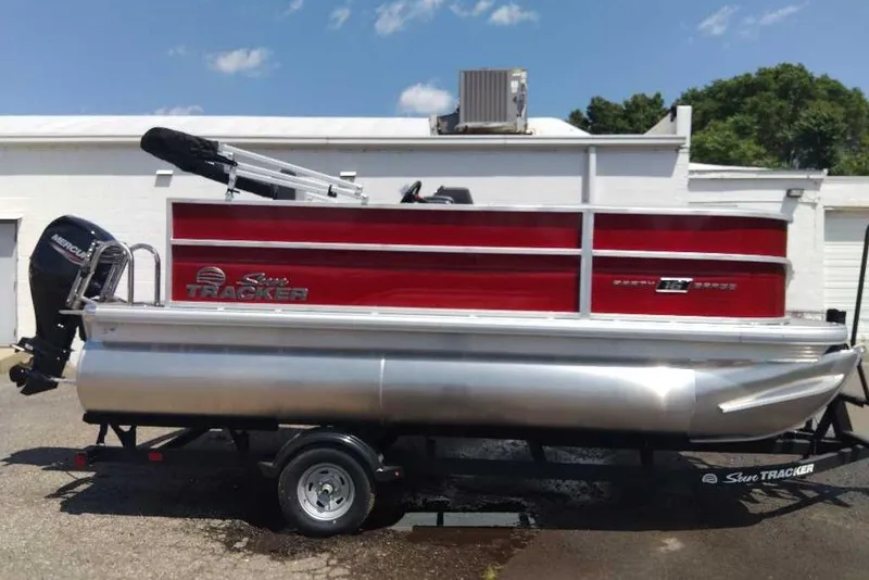 The Image of 2026 Sun Tracker Party Barge 16 DLX pontoon boat on trailer, red and silver design. - 0
