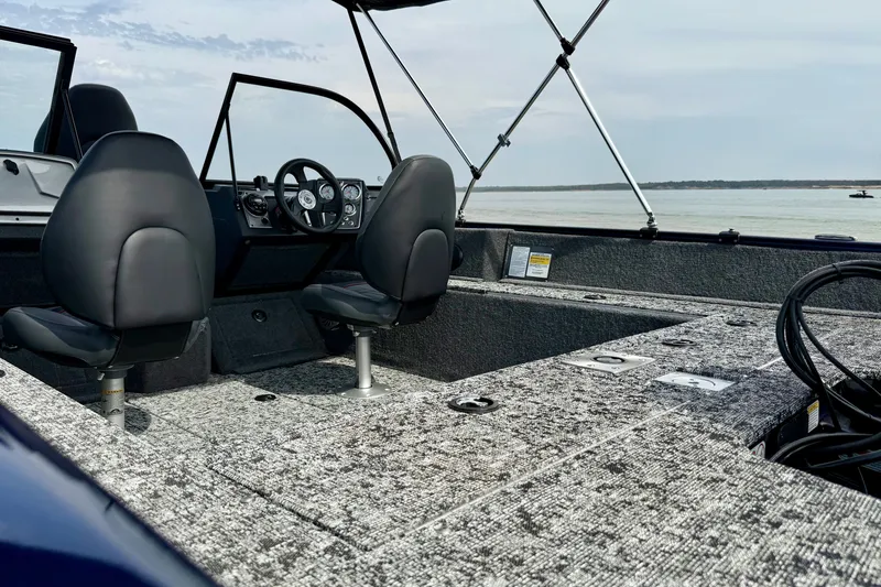 Slide: The Image of 2026 Tracker Pro Guide V-175 WT boat interior with seating and steering wheel, on a calm lake. - 14