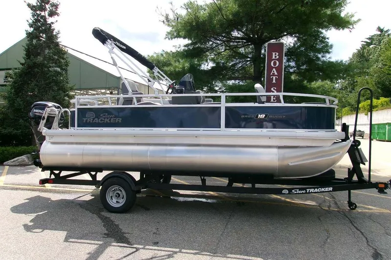 The Image of 2026 Sun Tracker Bass Buggy 18 DLX pontoon boat on trailer, parked outdoors. - 0
