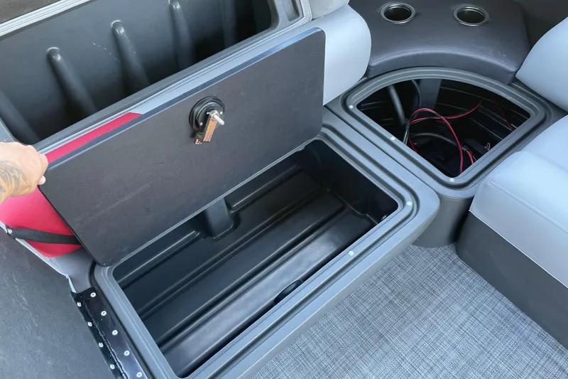 Slide: The Image of 2026 Sun Tracker Party Barge 20 DLX storage compartments with cup holders and wiring visible. - 14