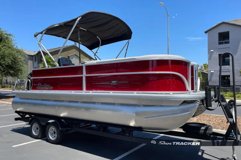 Slide: The Image of 2026 Sun Tracker Party Barge 20 DLX pontoon boat on trailer in parking lot. - 3
