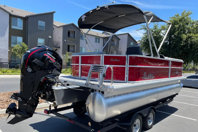 Slide: The Image of 2026 Sun Tracker Party Barge 20 DLX pontoon boat with Mercury engine, parked outdoors. - 2