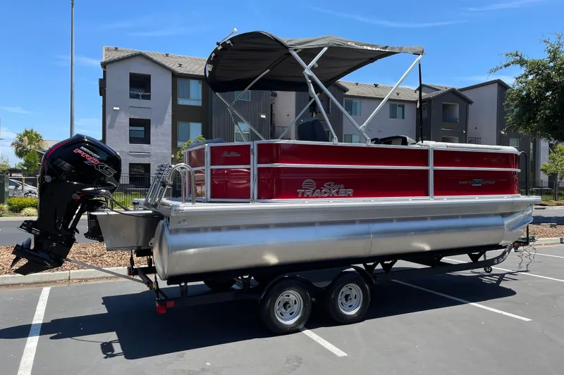 Slide: The Image of 2026 Sun Tracker Party Barge 20 DLX pontoon boat on trailer in parking lot. - 1