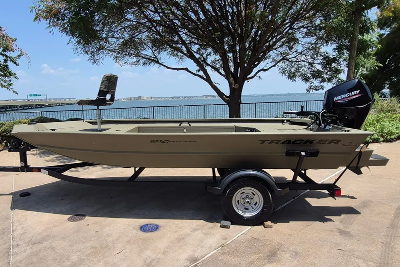 The Image of 2026 Tracker Grizzly 1654 T Sportsman boat on trailer by lakeside. - 0