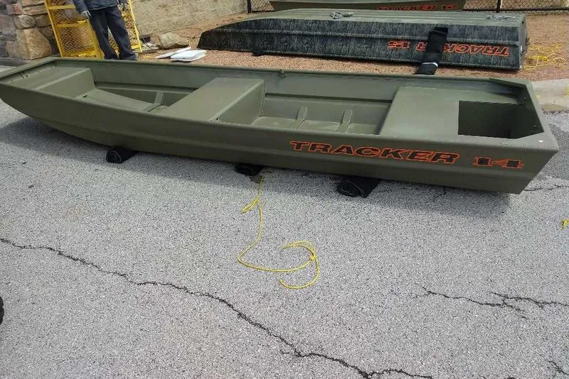 The Image of 2026 Tracker Grizzly 14 Jon boat on pavement, featuring olive green color and bold branding. - 0