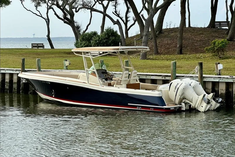 The Image of 2015 Chris-Craft 291 Catalina boat docked by a scenic waterfront with trees. - 0
