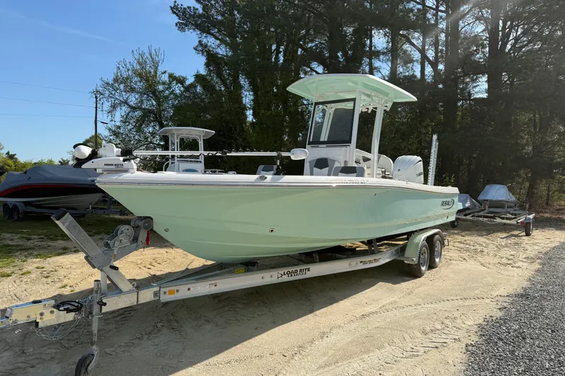 The Image of 2023 Robalo 246 Cayman boat on trailer, parked outdoors near trees. - 0