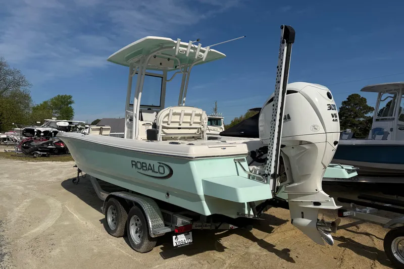 Slide: The Image of 2023 Robalo 246 Cayman boat on trailer, featuring Yamaha 300 V6 engine, parked outdoors. - 2