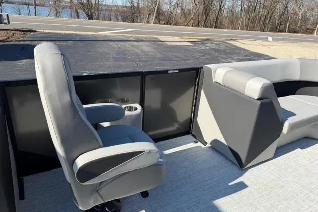 Slide: The Image of Alera A22Q 2026 boat interior with gray seating and cup holder, near a road and trees. - 33
