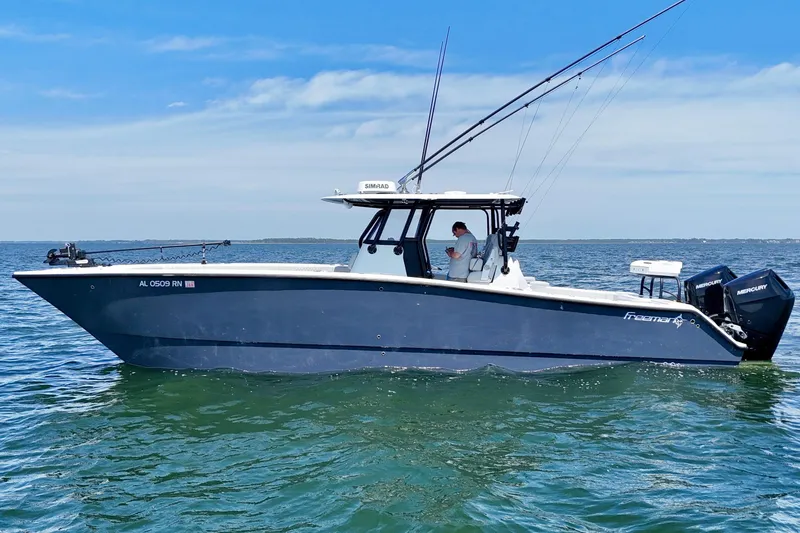 Slide: The Image of 2023 Freeman 34VH boat on calm water with fishing rods and dual Mercury engines. - 7