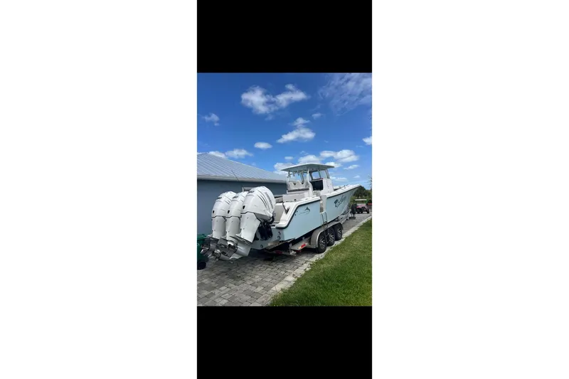 The Image of 2021 Streamline 35 CC boat with triple outboard engines on a trailer, under a blue sky. - 0