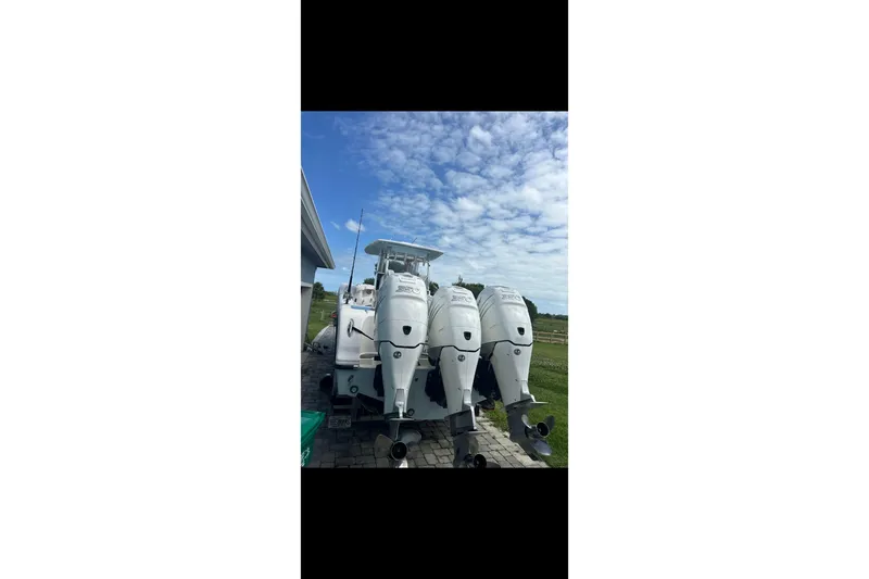 Slide: The Image of 2021 Streamline 35 CC boat on trailer beside house under clear blue sky. - 1