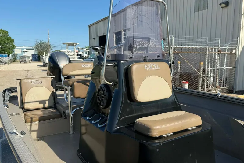 Slide: The Image of 2020 Excel 203 Bay Pro boat with beige seating and console, parked outdoors. - 12