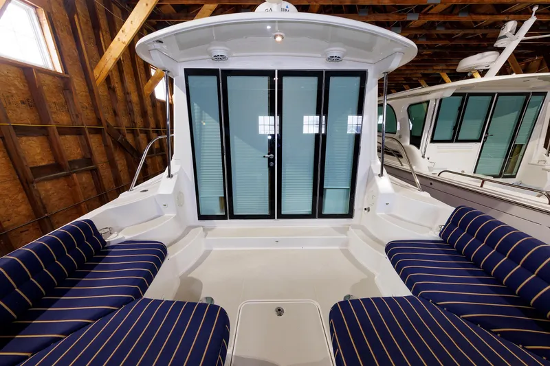 Slide: The Image of 2011 Back Cove 37 boat interior with striped seating and glass doors in a wooden boathouse. - 11