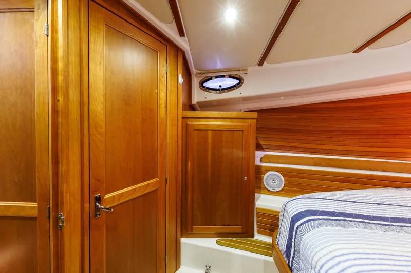 Slide: The Image of Luxurious wooden interior of a 2011 Back Cove 37 yacht cabin with striped bedding. - 17