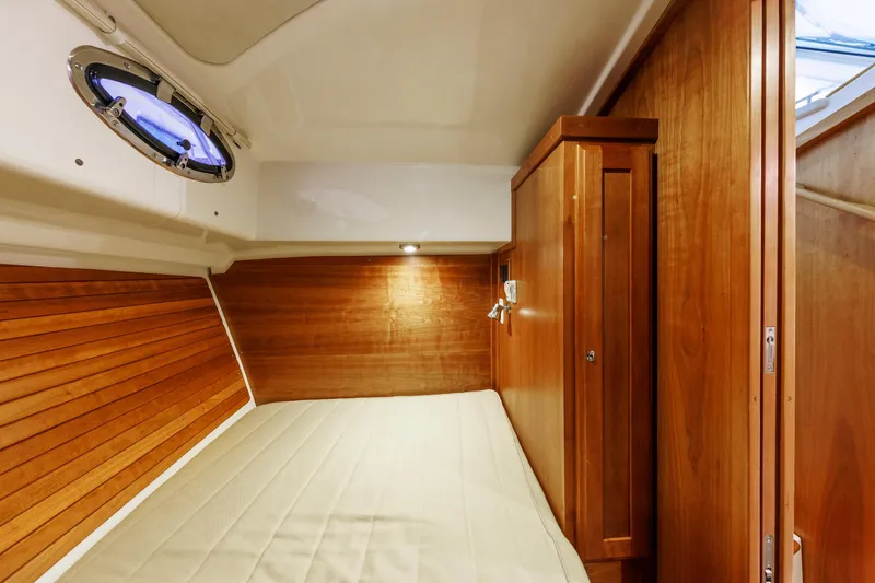 Slide: The Image of 2011 Back Cove 37 cabin interior with wooden paneling and porthole window. - 23
