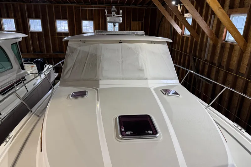 Slide: The Image of 2011 Back Cove 37 boat in wooden boathouse, front view with covered windshield. - 6