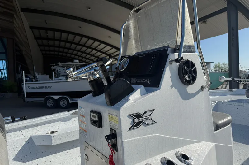 Slide: The Image of 2023 Xpress H22B Bay boat console with steering wheel and controls in a marina setting. - 11