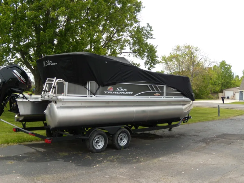 Slide: The Image of 2023 Sun Tracker Party Barge 20 DLX pontoon boat on trailer, covered, parked outdoors. - 7