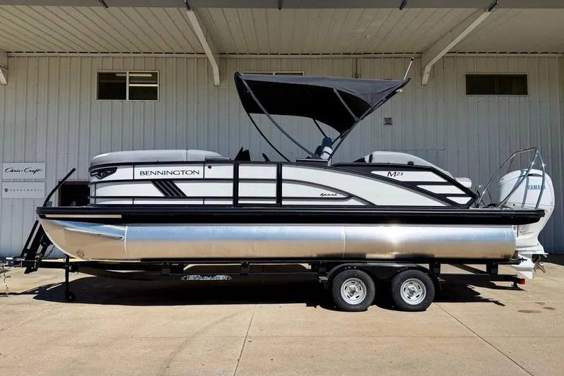 The Image of 2026 Bennington 23 M Swingback pontoon boat on trailer, parked outside a building. - 1