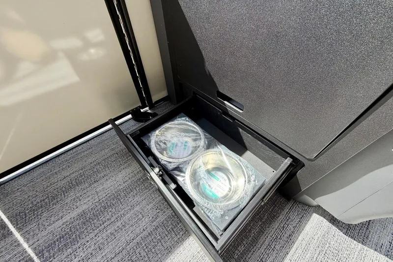 Slide: The Image of Storage compartment with packaged items in a 2026 Bennington 23 M Swingback boat. - 22