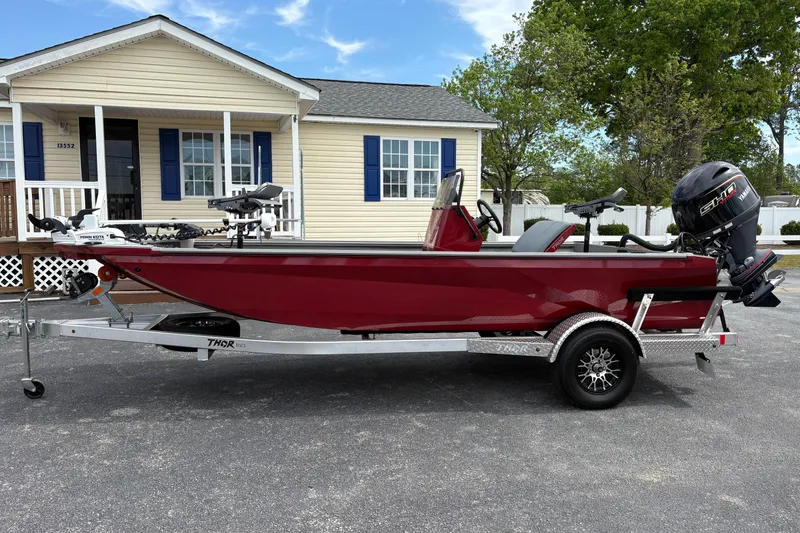 Slide: The Image of Red 2025 Thor Lake Hammer 1900CC Elite boat on trailer, parked in front of a house. - 2