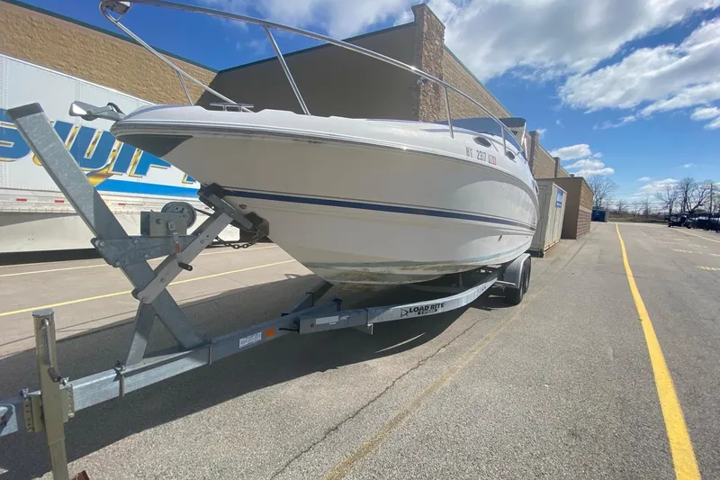 Slide: The Image of 2002 Chaparral Signature 240 boat on trailer, parked outdoors under a partly cloudy sky. - 2