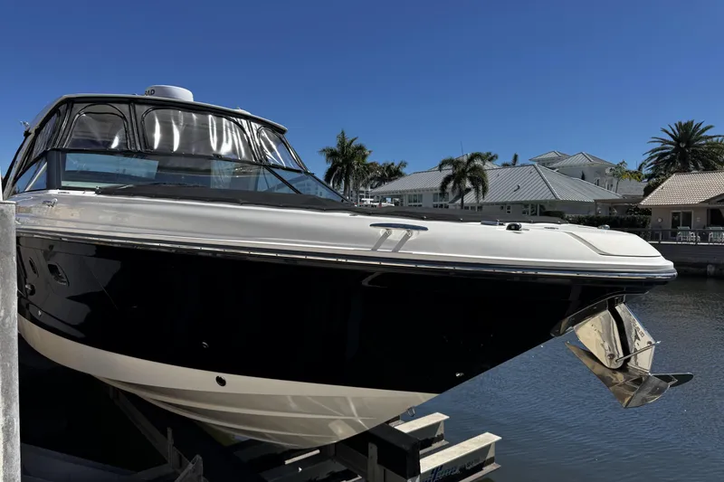 Slide: The Image of 2023 Sea Ray SLX 400 boat docked by waterfront homes under clear blue sky. - 13