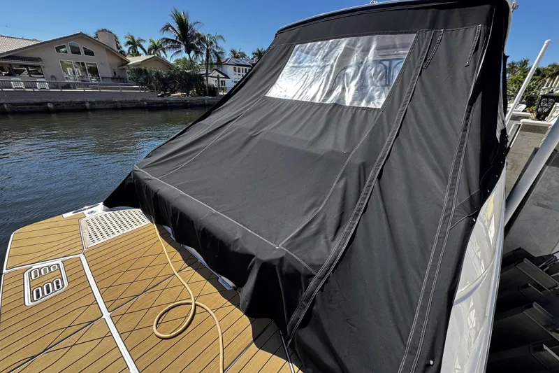 Slide: The Image of 2023 Sea Ray SLX 400 boat with black cover docked by waterfront homes. - 21