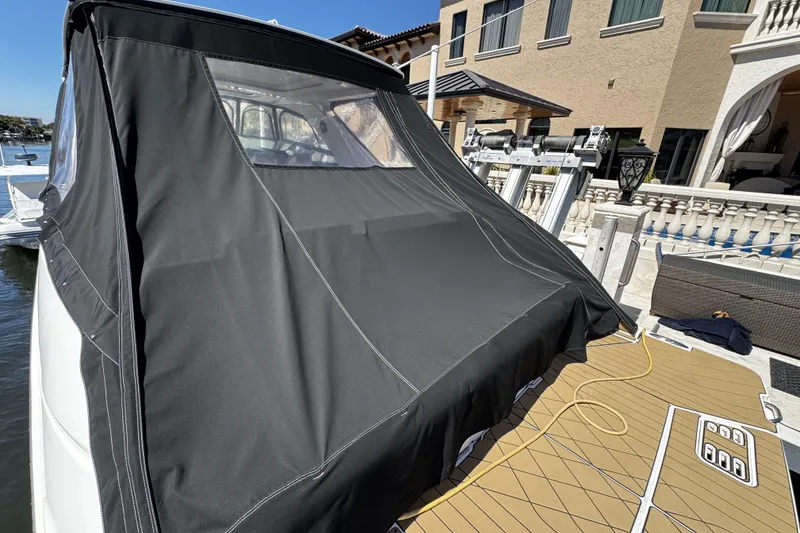 Slide: The Image of 2023 Sea Ray SLX 400 boat with black cover docked near waterfront property. - 22