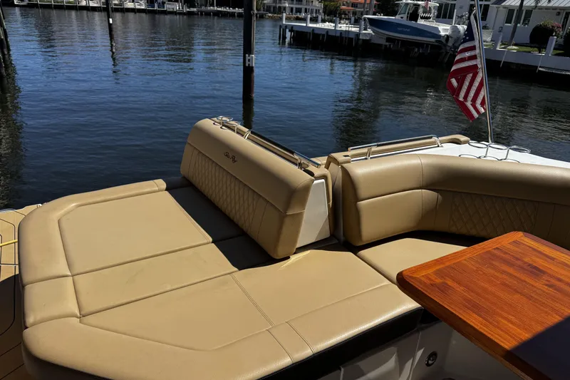 Slide: The Image of Luxurious seating on 2023 Sea Ray SLX 400 yacht, docked by waterfront with American flag. - 42