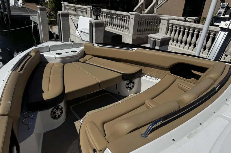 Slide: The Image of Luxurious seating area on 2023 Sea Ray SLX 400 boat, featuring tan upholstery and cup holders. - 52