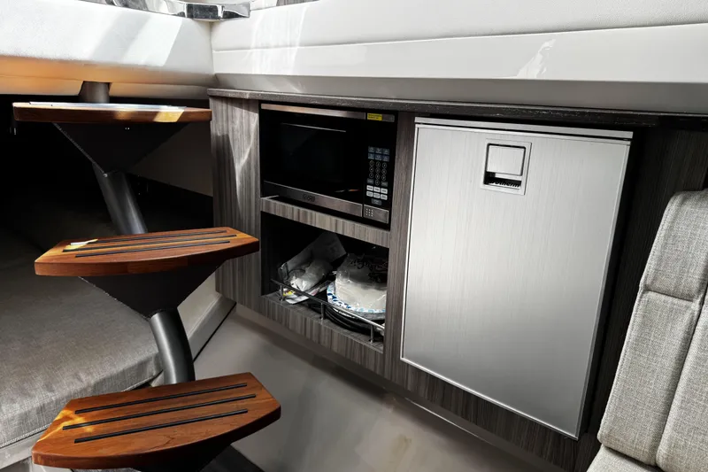 Slide: The Image of 2023 Sea Ray SLX 400 interior with microwave, fridge, and wooden steps. - 69