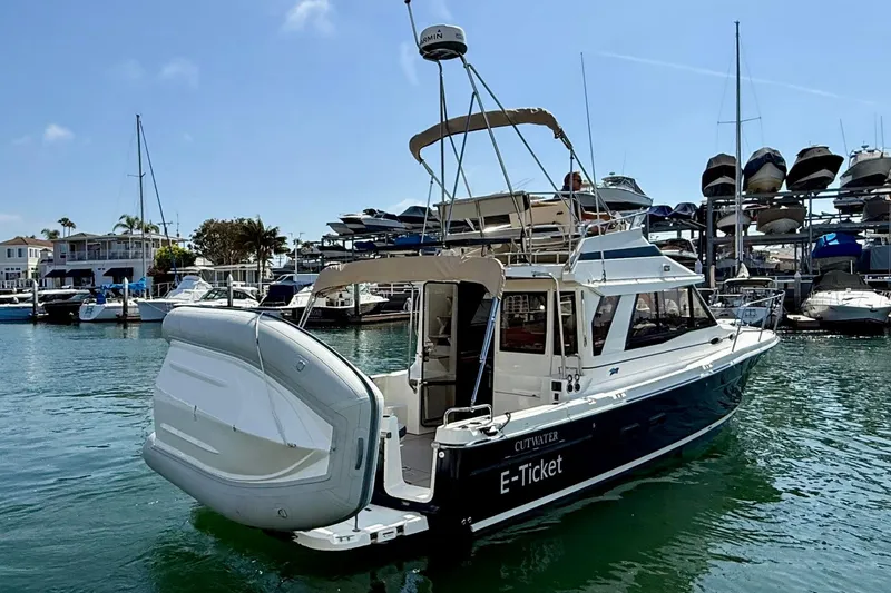 Slide: The Image of 2015 Cutwater C-30 CB boat docked in marina, featuring inflatable dinghy and flybridge. - 10