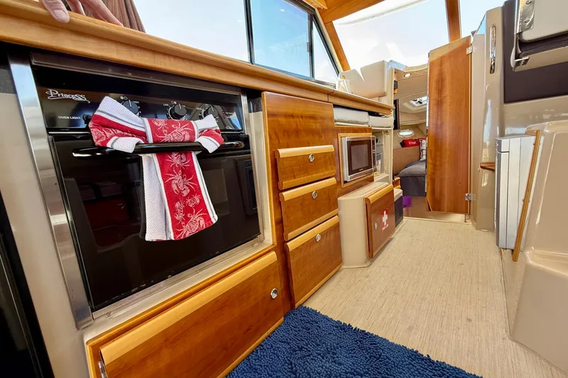 Slide: The Image of Interior of 2015 Cutwater C-30 CB boat featuring kitchen with oven and wooden cabinetry. - 22