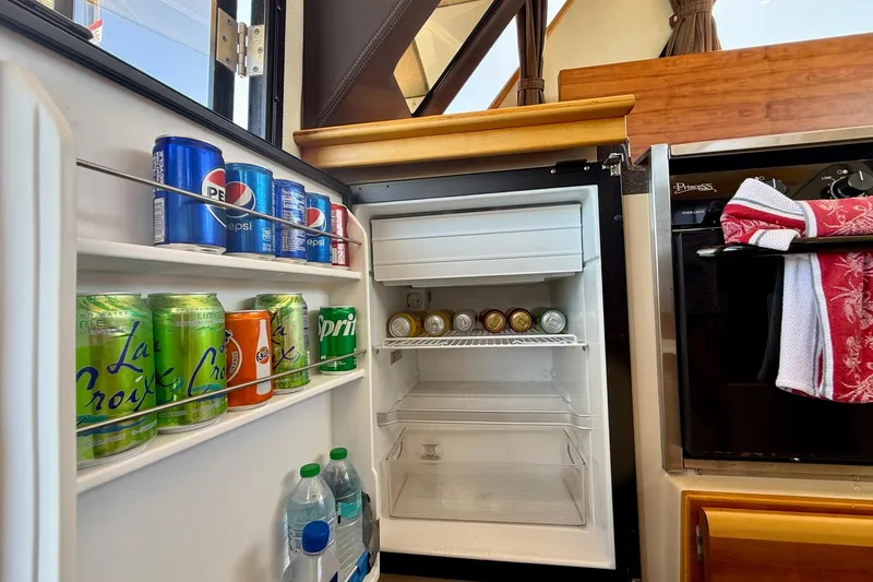 Slide: The Image of Mini fridge stocked with beverages inside a 2015 Cutwater C-30 CB boat kitchen. - 25